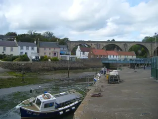 Lower Largo harbour with fishing boats, cottages, and the railway viaduct behind